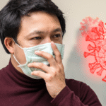Man wearing a face mask showing signs of illness, symbolizing symptoms of COVID-19 in 2025 with virus icons in the background.
